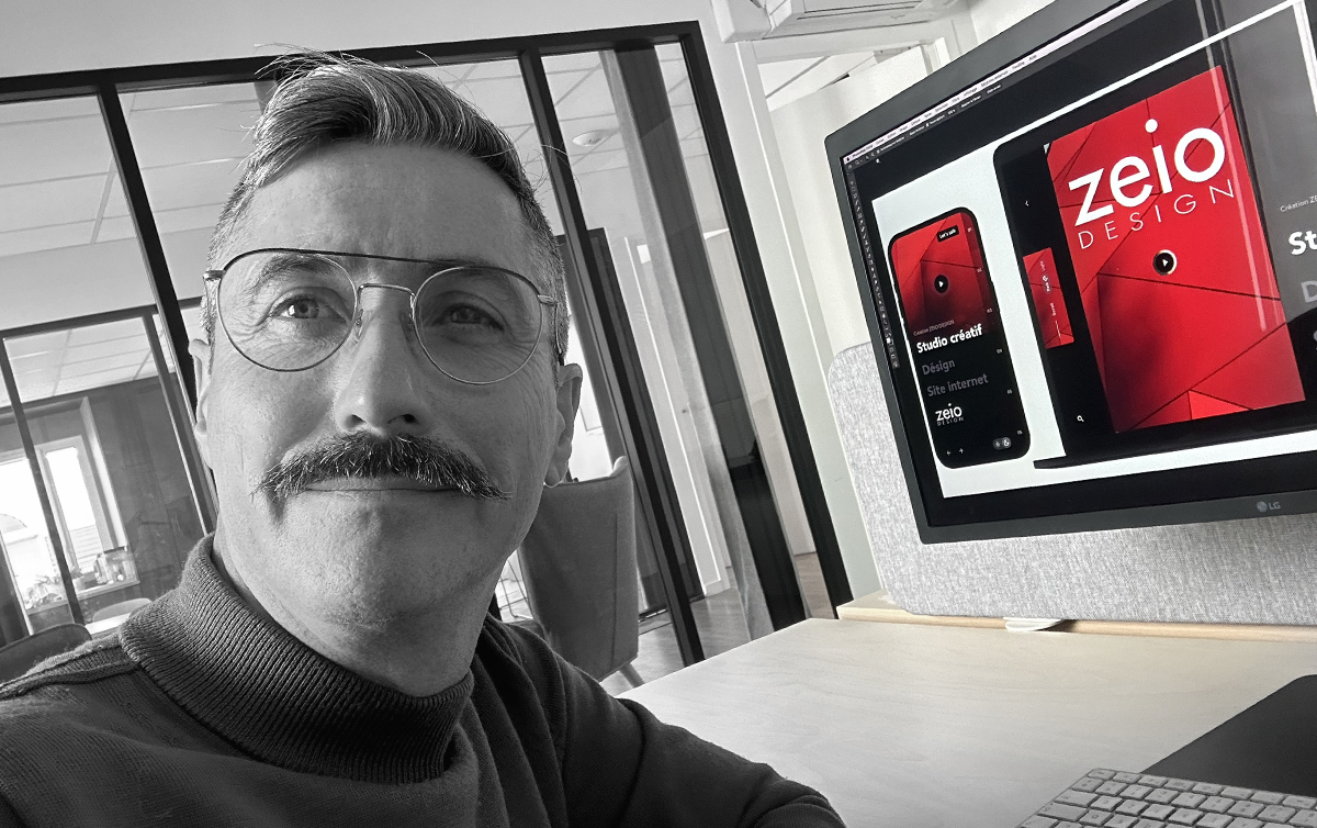 Homme travaillant sur ordinateur avec design à l'écran.